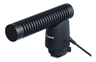 A black shotgun mic that is attached atop a DSLR camera, and provides more defined human voice recordings. .