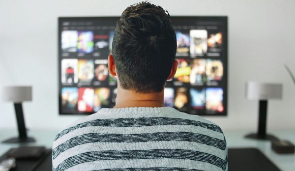 man on a striped shirt watching free netflix on tv