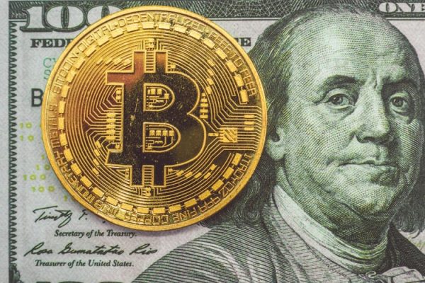 A bitcoin on a hundred dollar bill