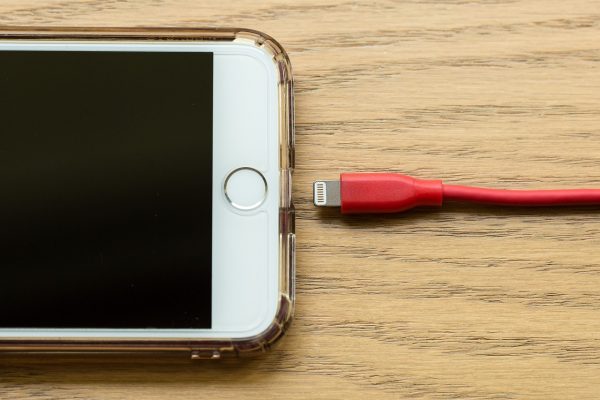 An iPhone with Touch ID and a lightning cable